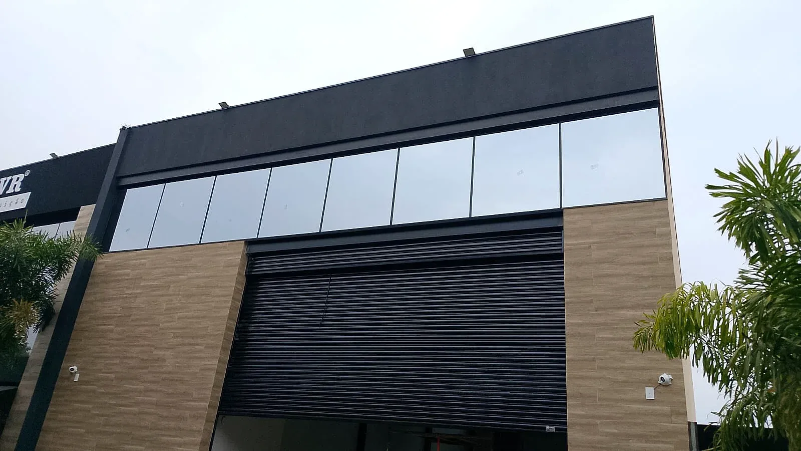 Faixa de vidros em esquadria de alumínio preto na fachada de galpão comercial