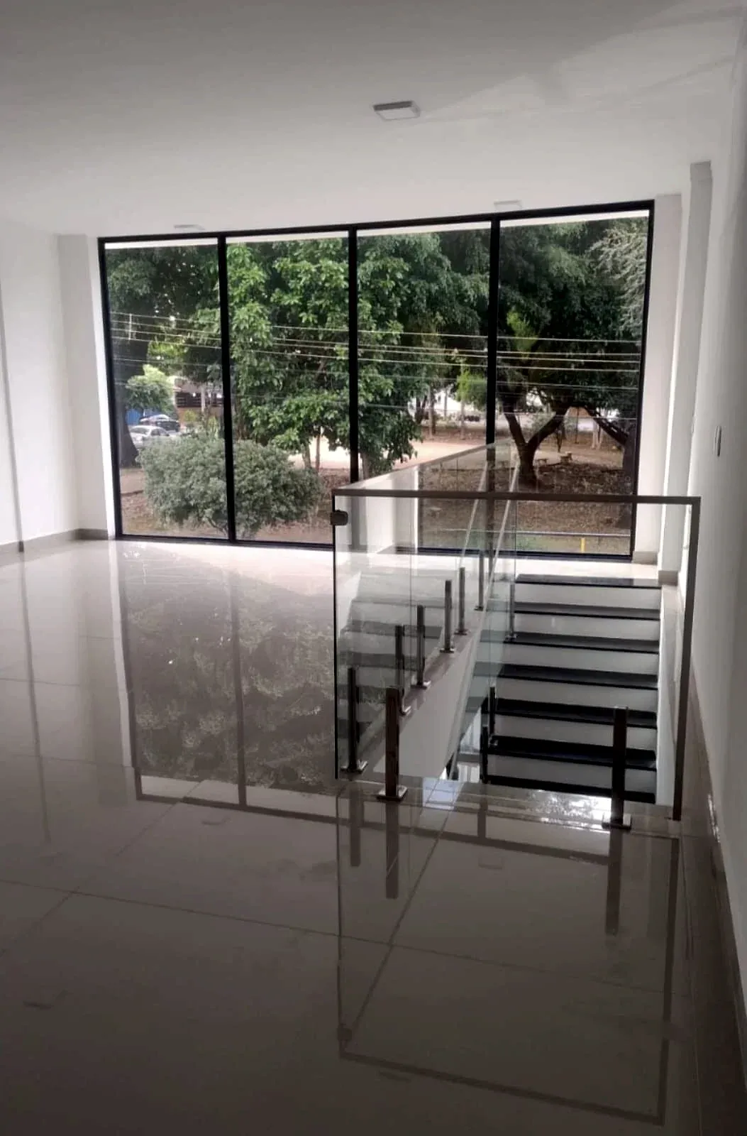 Fechamento em esquadria de alumínio preto do piso ao teto em sala com escada