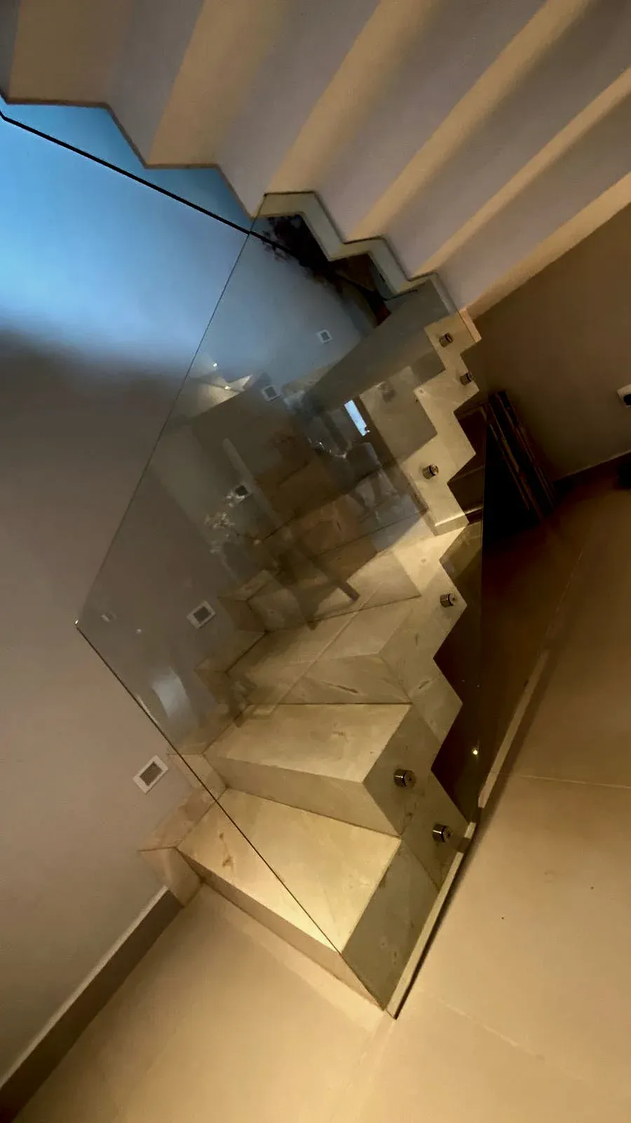 Guarda-corpo de vidro temperado fixado com botões de inox na lateral da escada