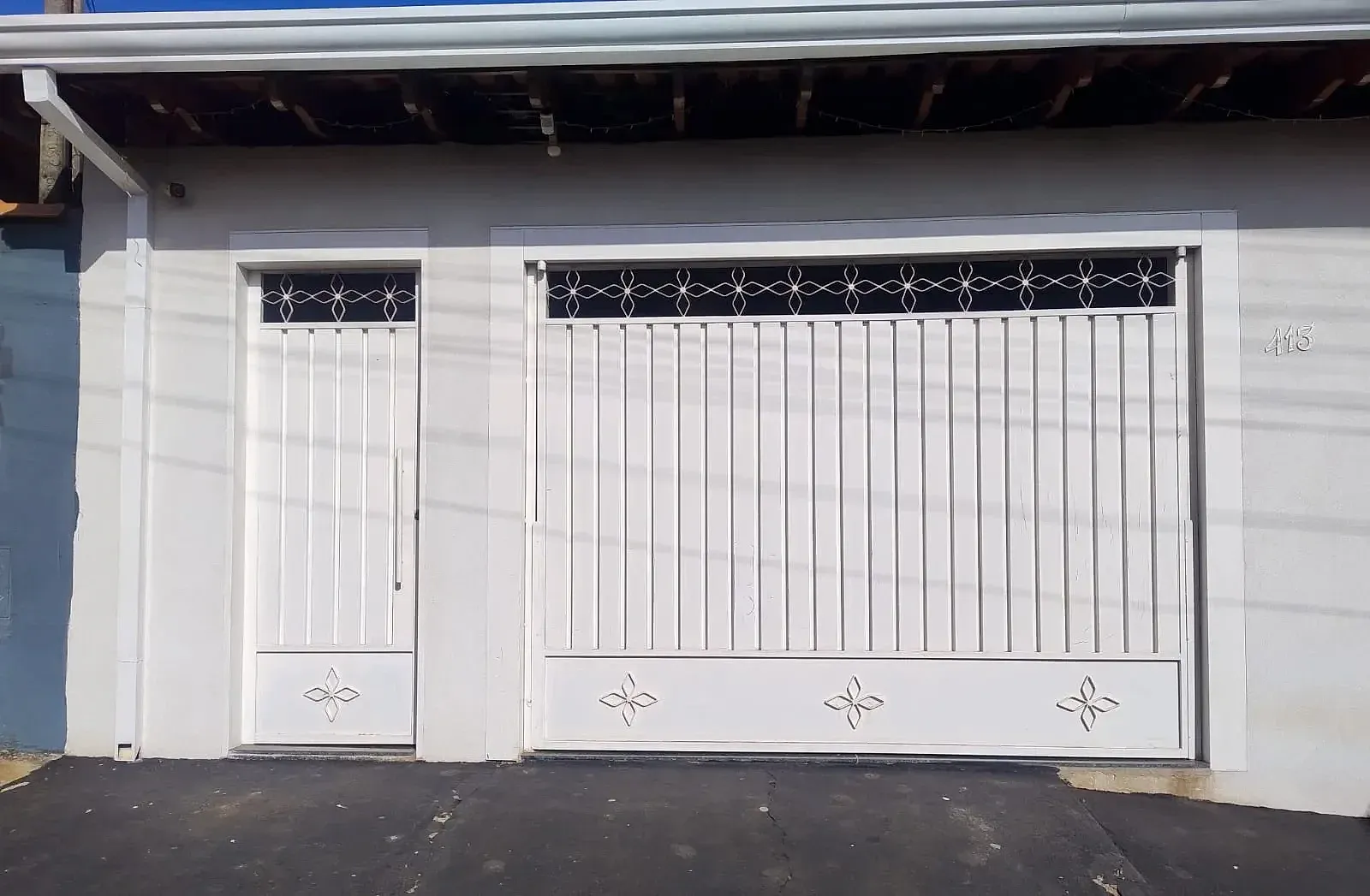 Portão e porta social de ferro branco com detalhes decorativos